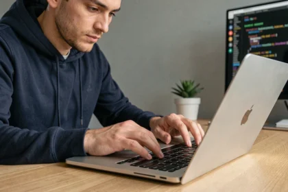 Développeur masculin tapant sur un clavier MacBook Pro dans un bureau moderne, illustrant l'utilisation du raccourci tilde sur Mac